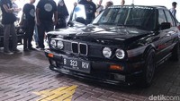 Orang berkerumun di mobil BMW hitam yang dimodifikasi.