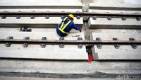 Petugas melakukan perawatan rel LRT.