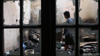 Seorang warga melintas di salah satu rumah yang terkena dampak kebakaran.