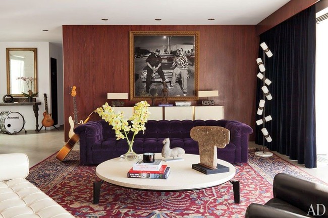 Interior bergaya art-deco mendominasi rumah ini. Tampak sofa beledu (velvet) berwarna ungu dengan dinding kayu yang dihiasi foto rapper Snoop Dogg dan Dr. Dre menjadi fokus di ruang keluarga. Foto: Dok. Architectural Digest