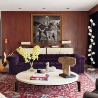 Interior bergaya art-deco mendominasi rumah ini. Tampak sofa beledu (velvet) berwarna ungu dengan dinding kayu yang dihiasi foto rapper Snoop Dogg dan Dr. Dre menjadi fokus di ruang keluarga. Foto: Dok. Architectural Digest