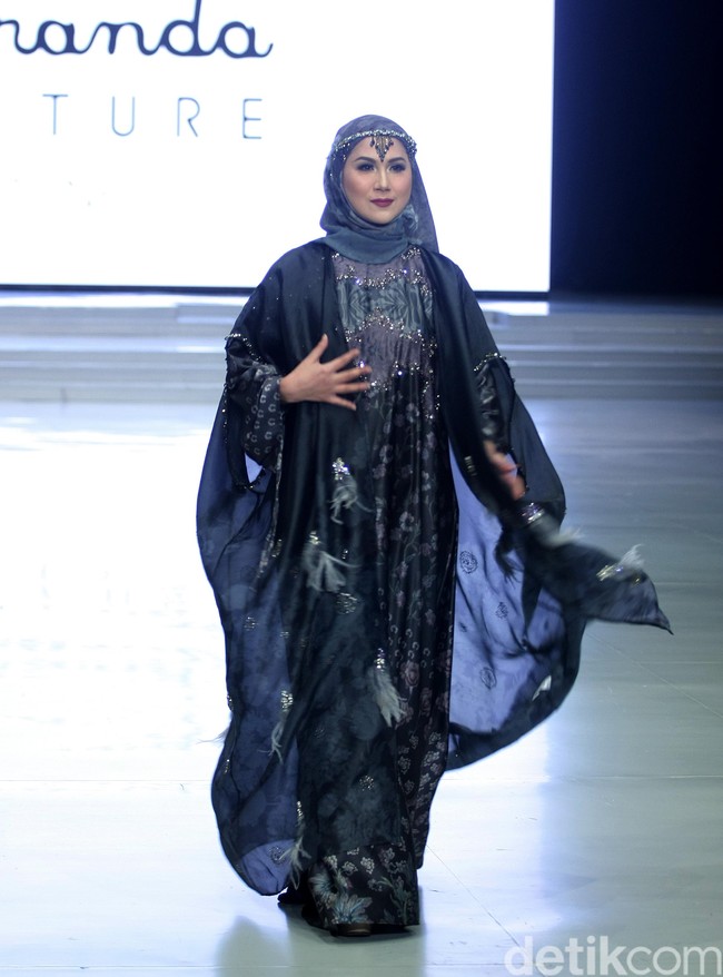 Marini Zumarnis menjadi muse pertunjukan desainer Ria Miranda. Ia tampil anggun memakai dress bernuansa ungu pastel dan headpiece yang berkilauan. Foto: Mohammad Abduh/Wolipop