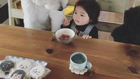 Mame, seorang gadis kecil asal Jepang dan sahabatnya Riku, anjing poodle yang menggemaskan memang sangat akrab. Mame yang sedang makanpun ditemani oleh anjing kesayangannya. Di meja juga terdapat cookies icing berbentung lucu dari sahabat ibu Mame. Foto: Instagram @tamaneqi.qoo.riku