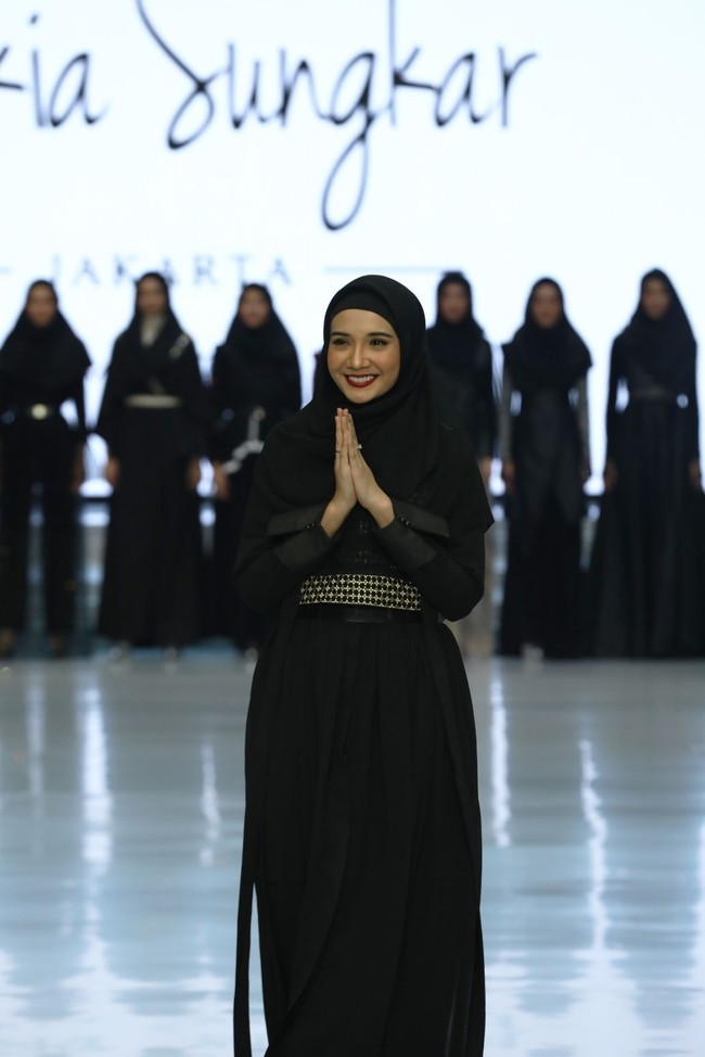 Menjadi salah satu desainer yang memamerkan karyanya di panggung IFW 2018, Zaskia Sungkar justru tak tampil berlebihan. Ia memilih tampil anggun dengan balutan dress dan shawl berwarna hitam, disempurnakan dengan belt berbahan metal keemasan. Foto: Doc. Wardah/Magnifique PR