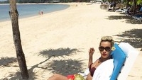 Asyik banget nih gaya Kimmy santai di pinggir pantai sambil menikmati kelapa muda alami.  Foto: Instagram @kimmyjayanti