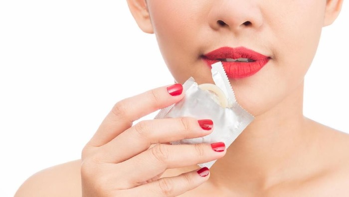 young woman asian girl mouth torn envelope condom on white background