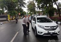 Polisi mengatur pengalihan arus lalu lintas akibat pohin tumbang melintang jalan.
