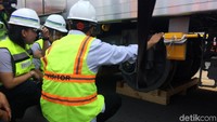 Menhub Budi Karya Sumadi didampingi Direktur Kontruksi PT MRT Jakarta Silvia Halim mengecek bagian bawah gerbong sambil jongkok.