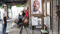 Salah satu pengunjung memperhatikan dengan detail lukisan Dwayne Johnson.