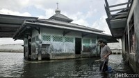 Seorang warga mencari ikan di sekitar musala.