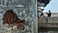 Dua orang remaja foto-foto di bangunan yang terendam rob.