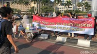 Relawan Jokowi Connection (J.Co) membentangkan spanduk di Bundaran Patung Kuda, Jakarta, Minggu (8/4/2018).