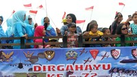 Sejumlah masyarakat hadir menyaksikan upacara HUT TNI AU sambil membawa atribut seperti bendera merah putih.