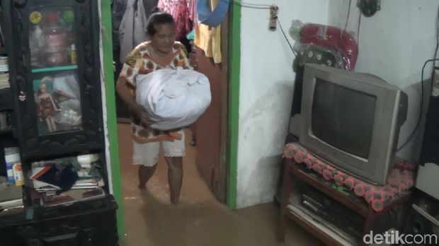 Warga mengamankan barang-barangnya agar tak terkena air banjir.