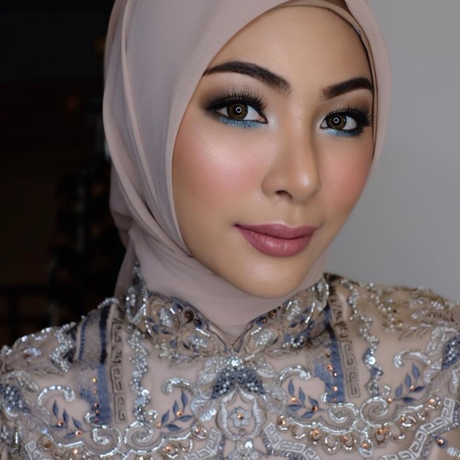 Tampil memakai hijab Ivan Gunawan, Faye mendapatkan riasan glamour dari makeup artist Indonesia, TEDZAmakeup. Riasan mata smokey eyes membuat matanya jadi lebih tegas. Foto: Instagram