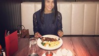 Sendirian aja nih? Bergaun hitam, Melly menyantap steak di Hard Rock Cafe Singapura. Foto: Instagram melly.bradley