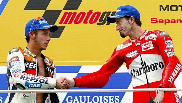 MotoGP rider Italian Max Biaggi (R) shakes hands with his compatriot and world champion Valentino Rossi after winning the 2002 Malaysian Motorcycle Grand Prix at the Sepang international circuit, 13 October 2002. Biaggi won the race with a time of 4401.592 whie Valentino Rossi finished second and Brazilian Alex Barros came in third.  AFP PHOTO / Jimin LAI / AFP PHOTO / JIMIN LAI