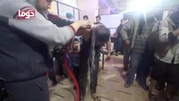 Salah satu warga Suriah membungkukkan badan agar air mengalir bisa membasuh bekas serangan kimia di badannya. Foto: White Helmets/Handout via REUTERS