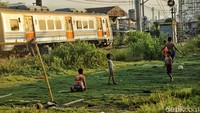 Anak-anak tampak terbiasa dengan kehadiran kereta api. Mereka tetap asyik bermain bola saat kereta api sedang melintas.
