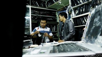 Seorang pengunjung tengah berkonsultasi mengenai kerusakan laptop kepada pemilik toko yang bernama Pak De alias Suharjo.