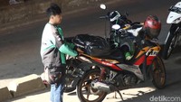 Driver ojek online menata barang milik pelanggan yang siap diantara di tengah jalan.