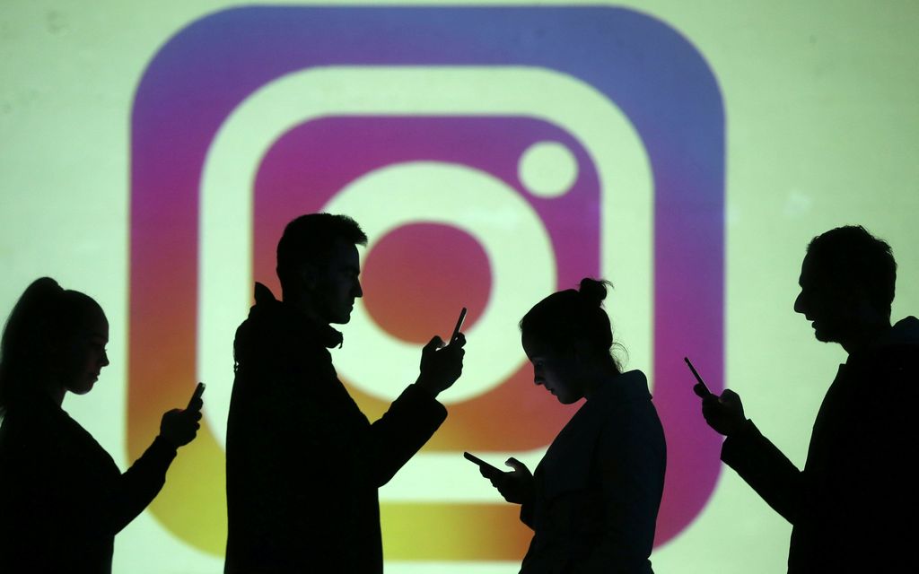 REFILE - CLARIFYING CAPTION Silhouettes of mobile users are seen next to a screen projection of Instagram logo in this picture illustration taken March 28, 2018.  REUTERS/Dado Ruvic/Illustration
