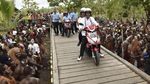 Foto: Jokowi-Iriana Boncengan Motor Menembus Hujan di Asmat