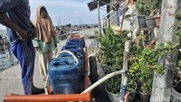 Seorang warga di Muara Kamal sedang antre untuk mendapatkan air bersih.