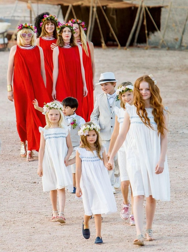 Untuk memberi kesan kontras, para bridesmaid menggunakan dress merah menyala dengan crown bunga sebagai hiasan kepala.  Foto: dok. Edward Haynes & Roo Kendall