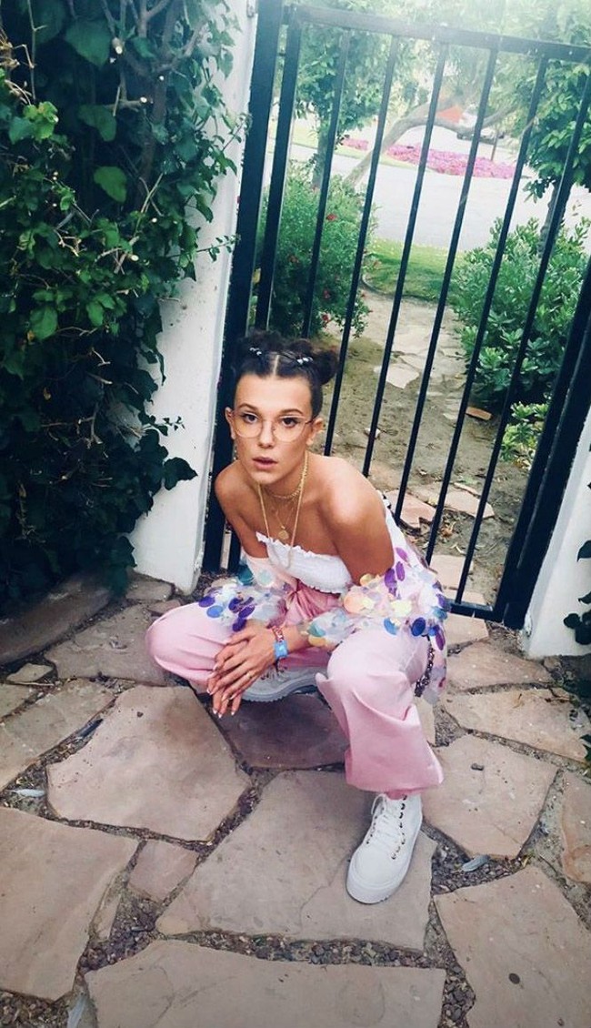 Crop top dan celana warna pastel yang feminin semakin mencuri atensi dengan jaket statement ala Millie Bobby Brown. Foto: Instagram