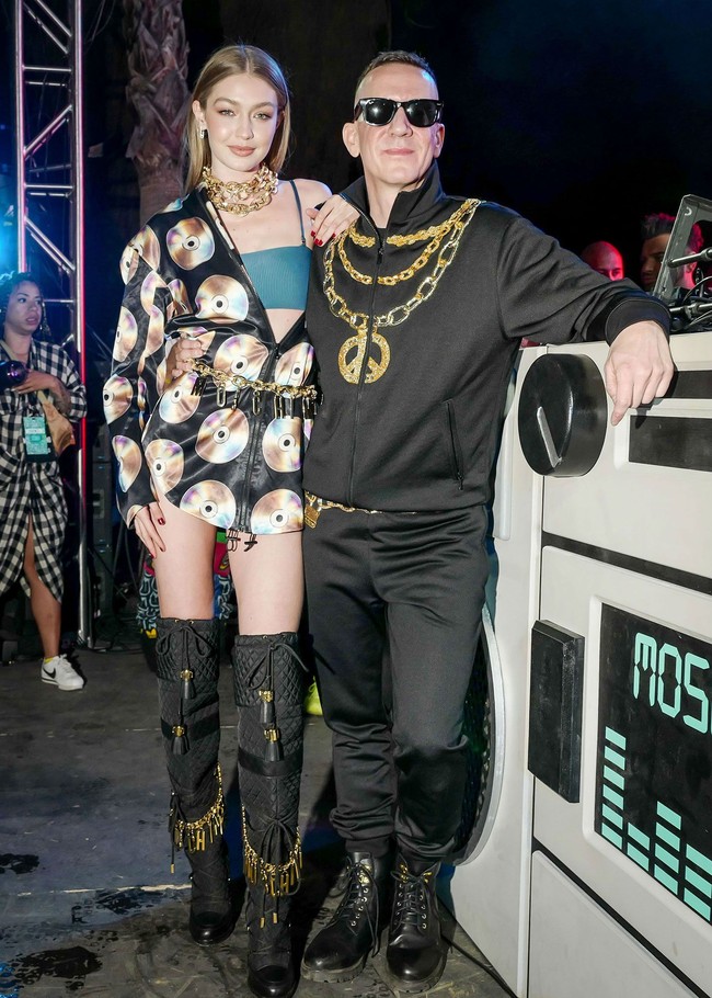Berpose dengan Jeremy Scott, Gigi Hadid mengenakan jaket windbreaker bergambar kepingan CD dan berbagai aksesori emas khas gaya rapper Amerika. Busananya kali ini adalah koleksi Moschino x H&M. Foto: Instagram