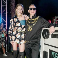 Berpose dengan Jeremy Scott, Gigi Hadid mengenakan jaket windbreaker bergambar kepingan CD dan berbagai aksesori emas khas gaya rapper Amerika. Busananya kali ini adalah koleksi Moschino x H&M. Foto: Instagram