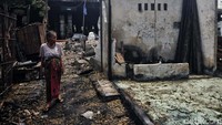 Seorang ibu melihat rumahnya yang ludes terbakar.