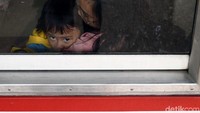 Ekspresi seorang anak saat ikut ibunya duduk di kursi prioritas di dalam kereta.
