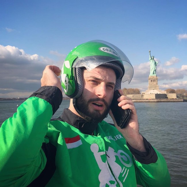 Si ganteng ojek bule ini kerap berpose di berbagai negara yang didatanginya dengan memakai jaket ojek online kesayangannya. Posenya pun lengkap dengan helm ojek online. Foto: Dok. Instagram OjekBule