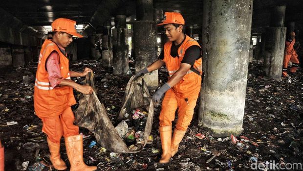 Pasukan oranye mengangkut sampah secara manual