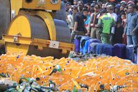 Alat berat gilas barang bukti botol isi miras. 