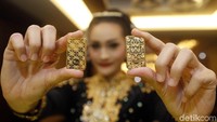 Seorang model menunjukan emas batangan seri batik terbaru.