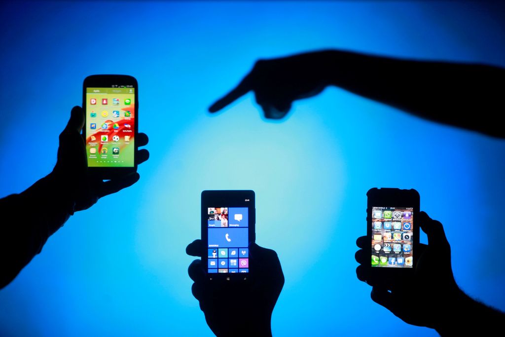 FILE PHOTO: Men are silhouetted against a video screen as they pose with smartphones in this photo illustration May 17, 2013. REUTERS/Dado Ruvic/File Photo