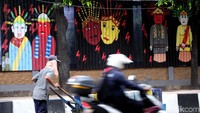 Warga tengah melintas diantara mural bergambar Ondel-ondel.