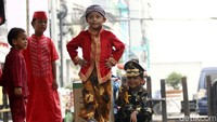 Seorang pria cilik dengan percaya diri berjalan di peragaan busana.
