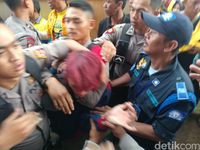 Seorang pemuda berambut merah dibawa petugas keamanan. 