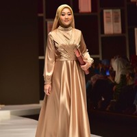 Mengenakan gaun panjang bernuansa emas metalik, Atalia melenggang di runway dengan gaya hijab modern berwarna senada. Foto: Instagram/@rya_baraba