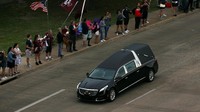 Warga tampak melambai-lambaikan bendera Amerika Serikat di pinggir jalan. (Foto: Dok. REUTERS/Spencer Selvidge)