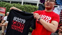 Seorang penjual memamerkan kaus #2019GantiPresiden di depan kamera.
