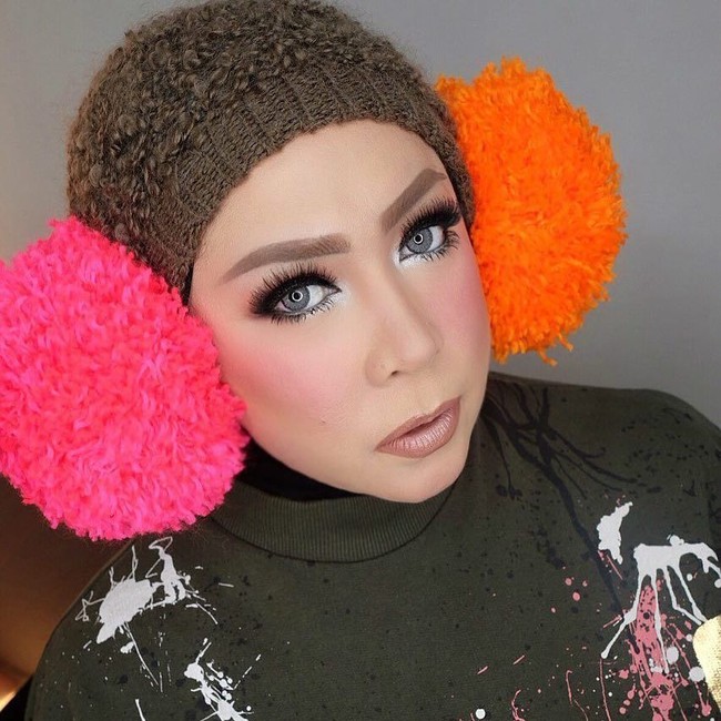 Melly Goeslaw tampil menarik perhatian memakai topi rajut warna netral di atas ciput hitamnya. Pom-pom pink dan oranye yang terpasang seperti menutup telinganya membuat penampilannya semakin mencolok. Foto: Instagram melly_goeslaw