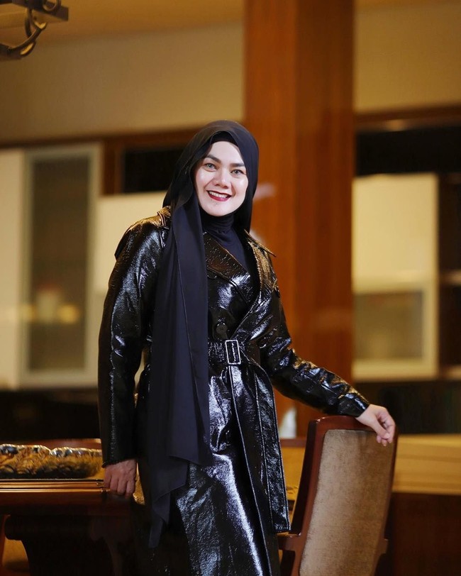 Gaya serba hitam dengan padu padan coat patent leather, turtle neck dan jilbab modern. Bisa jadi inspirasimu yang ingin tampil monokrom tapi tak ingin terlihat membosankan. Foto: Instagram/@queen_saritaabdulmukti