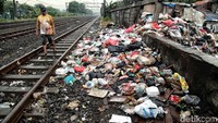 Seorang warga melintas di depan tumpukan sampah.
