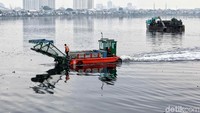 Ekskavator menyusuri waduk untuk membersihkan sampah dan tanaman air.