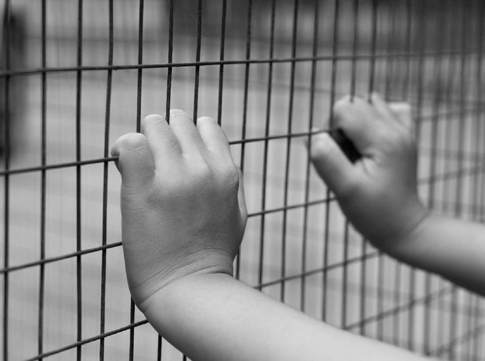 Hand of prisoner grabbed the metal  fence in black and white